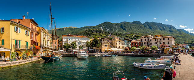 Malcesine, Italy - September, 3. 2019: Tourists at the harbor of Malcesine. Malcesine is located at Lake Garda. In background is a mountain range.