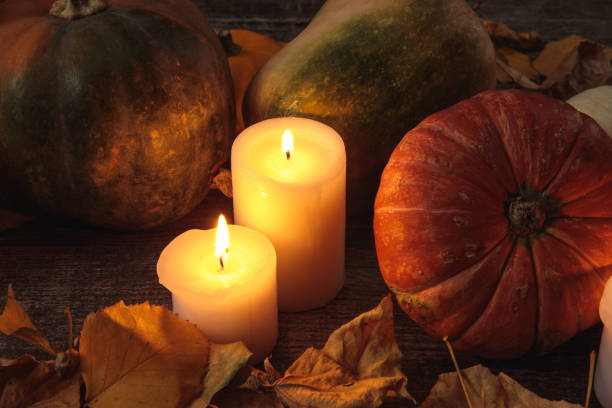 dry foliage, burning candles, ripe pumpkin on wooden rustic table