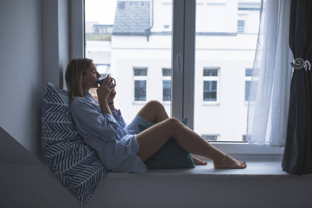 istock Young woman relaxing on window sill 1180197879