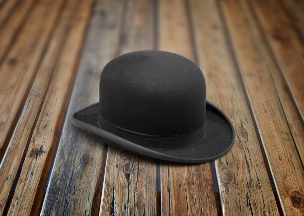 A stylish black bowler hat on textured wooden table