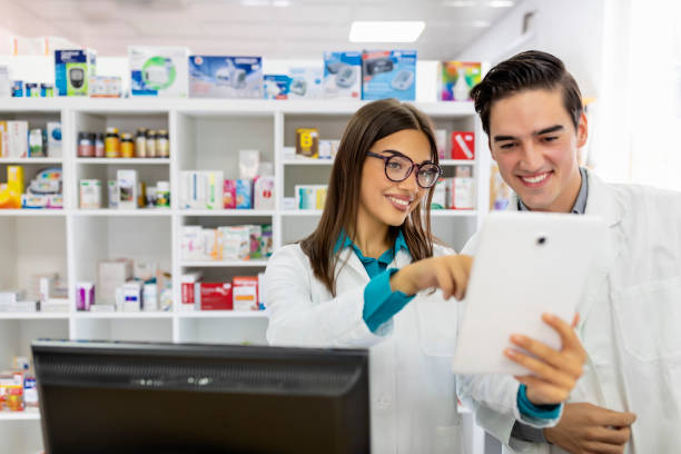 Two cheerful pharmacists working together. Two cheerful pharmacists working on medicines inventory at hospital pharmacy. healthcare and medicine business hospital variation stock pictures, royalty-free photos & images