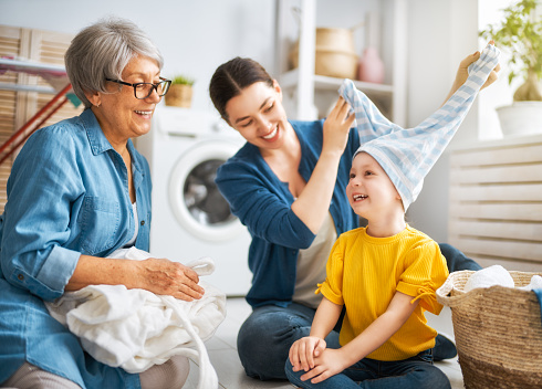grandma, mom and child are doing laundry at home. three generations of family