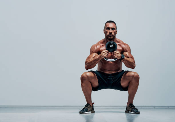 Handsome Muscular , Cross Training Athlete Doing Squats With Kettlebell stock photo
