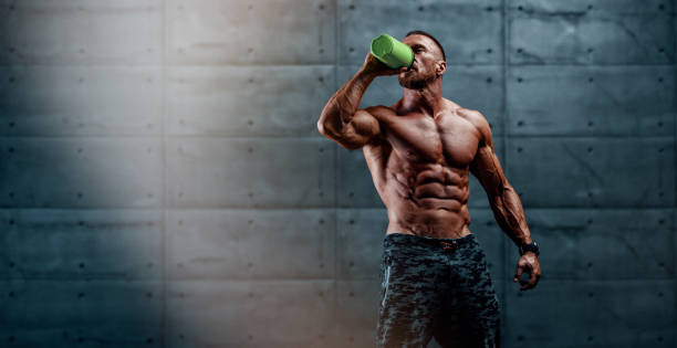 Nutritional Supplement. Muscular Men Drinks Protein, Energy Drink After Workout stock photo