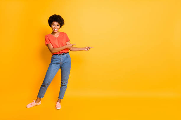 copyspace full length body size photo of nice charming pretty sweet girl black presenting you something proposing wearing t-shirt jeans denim isolated with yellow vivid color background - blank sale young women one young woman only imagens e fotografias de stock