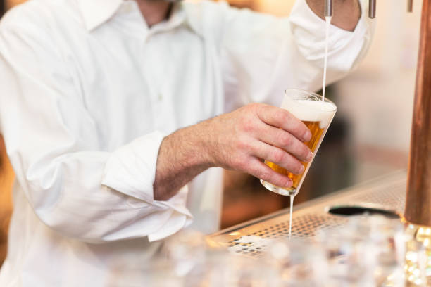 Pouring beer for client. Bartender pouring beer while standing at the bar counter.