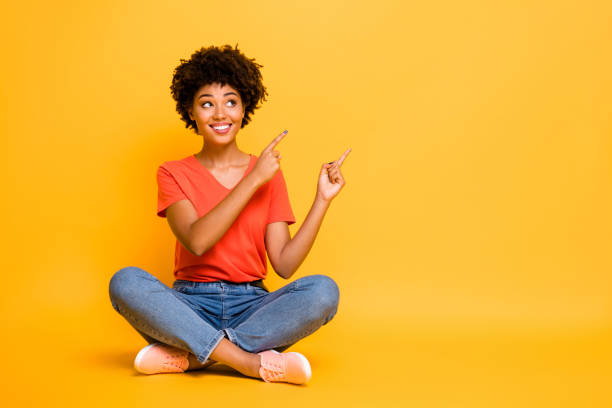 photo de copyspace de charmante petite amie magnifique et gaie et attirante s'asseyant avec des jambes croisées portant des chaussures en denim de jeans d'isolement avec le fond lumineux jaune de couleur lumineuse - sitting on a chair photos et images de collection