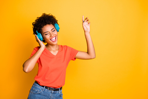 Photo of cute charming curly wavy trendy attractive black american, girlfriend wearing t-shirt jeans denim dancing singing with her eyes closed isolated over yellow vivid color background