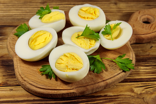 Boiled eggs with parsley on cutting board on a wooden table