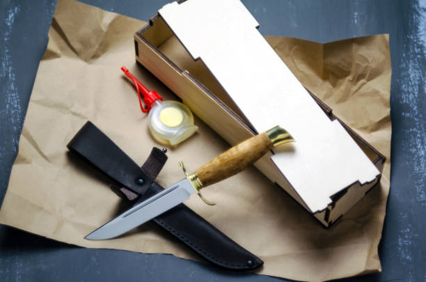 istock Knife with a fixed handle in a gift box with leather sheath and oil for impregnation on paper and a dark background. 1180206835