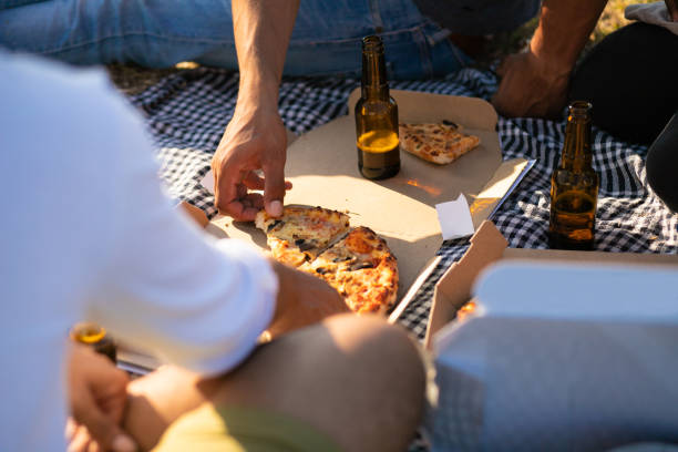 Hand of man taking slice of pizza from box