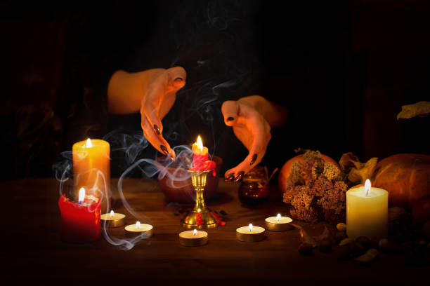 istock Witch guessing on wax on the altar in the dark. Female hands with sharp black nails making passes above candles, pumpkin, nuts, magic herbs, dry leaves, selected focus, low key 1180208602