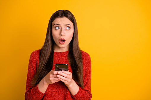 Photo of terrified stunned, shocked horrified youngster holding telephone receiving negative feedback having forgotten her password to social media isolated vibrant color background