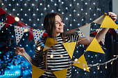 Woman at home hanging christmas lights party flags decorate items for celebration new year