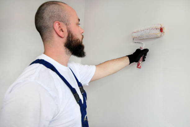 istock Construction worker doing finish renovation at apartment. Professional painter contractor using white paint roller brush painting of concrete wall room on construction site. Home renovation concept. 1180213170