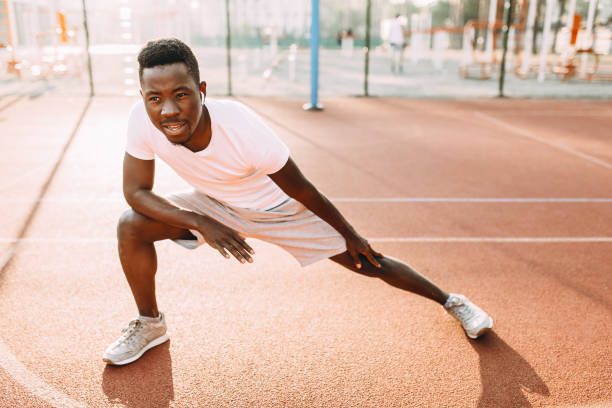 istock Athletic African-American doing stretching exercises, preparing for morning training at the stadium 1180213883