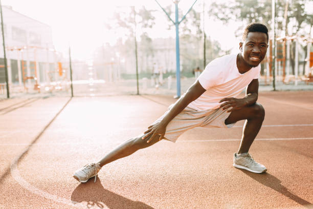 istock Athletic African-American doing stretching exercises, preparing for morning training at the stadium 1180213962