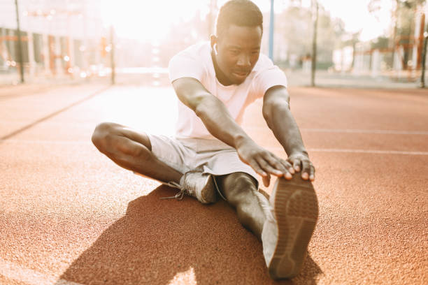 istock Athletic African-American doing stretching exercises, preparing for morning training at the stadium 1180213975