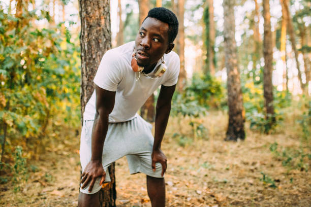 istock A man rests against a tree with his hands on his knees after a morning jog. 1180214456