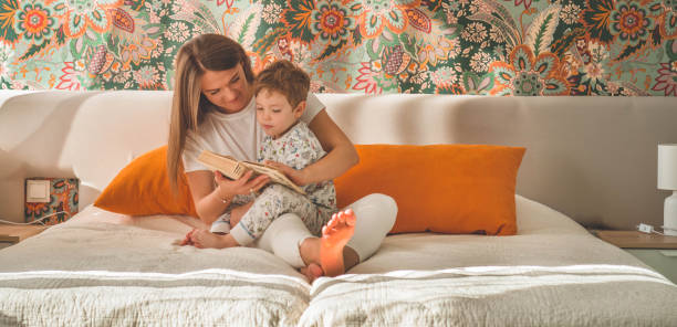 istock Pretty young mother reading a book to her little son in modern interior 1180215549
