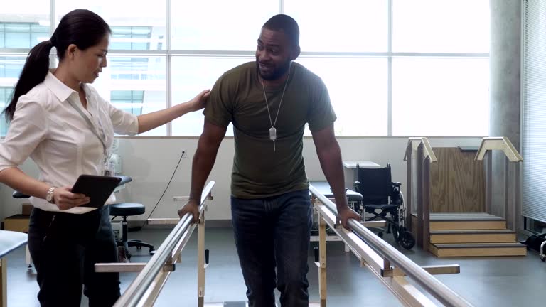 Physical therapist helps military patient on parallel bars