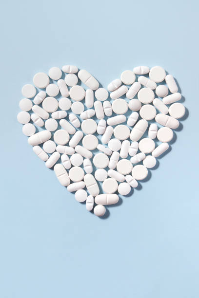 istock Heart Shaped White Pills on Blue Background 1180220131