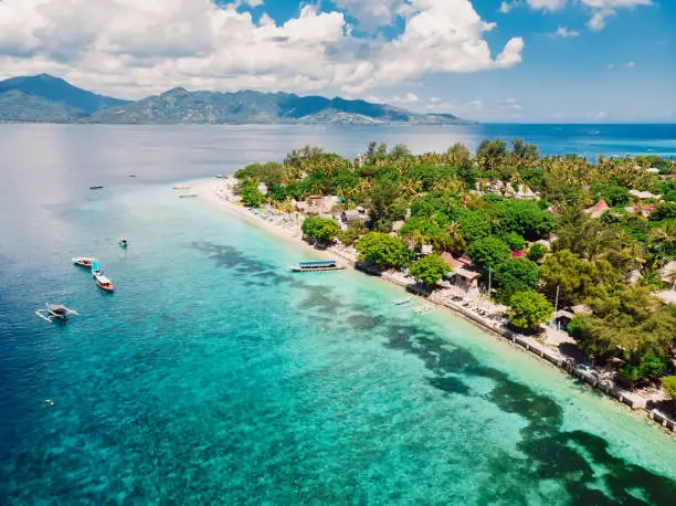 Tropical island with beach and turquoise transparent ocean, aerial view. Gili islands