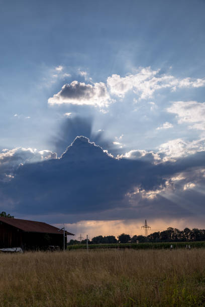 istock Changing Weather with Sunbeams above Field with Hut, Germany 1180221779