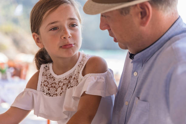 Little girl on a bridge of tears looking at her serious father giving her a lecture about something she did wrong. Father shouting at young daughter