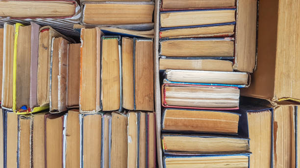 istock Many sorted old books are stacked as a background front view. Stack of used old books in the school library. Old and used hardback books or textbooks are visible from above 1180224425