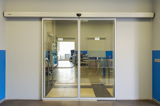 Empty sliding glass front door at the airport. Glass doors in the office. Glass entrance. Entrance to administration building equipped with automatic door