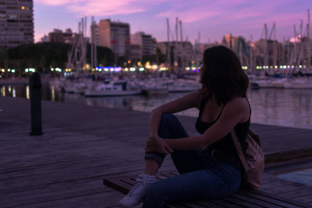 istock Young woman is sitting on a bench in a harbor 1180224739