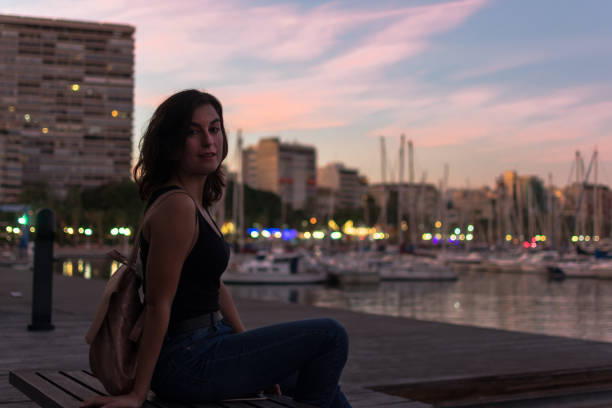 istock Young woman is sitting on a bench in a harbor 1180224747