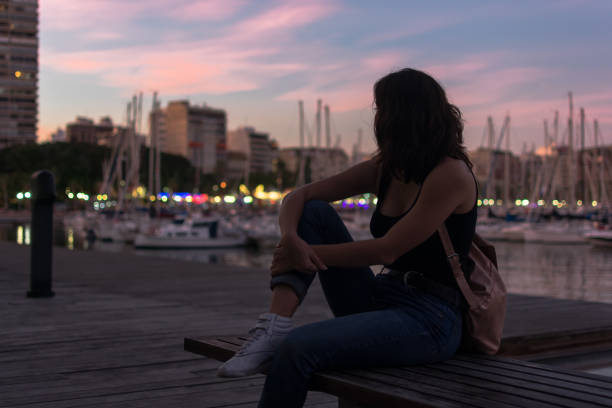istock Young woman is sitting on a bench in a harbor 1180224771