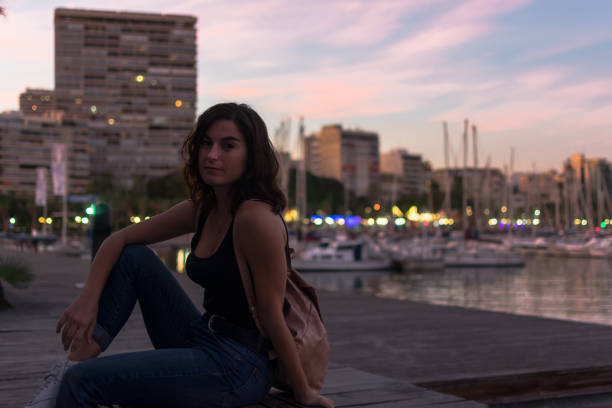 istock Young woman is sitting on a bench in a harbor 1180224792