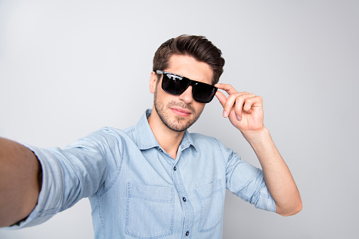 Photo of white cheerful attractive handsome man taking selfie holding his sunglass, touching bearded isolated over grey color background