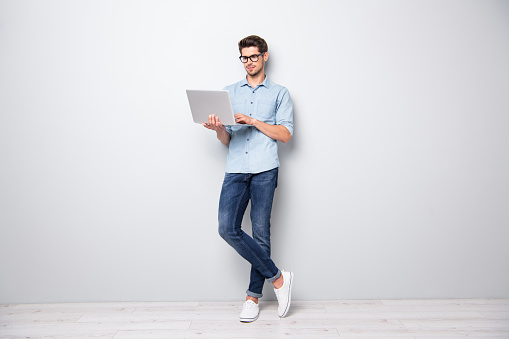 Full length body size photo of focused serious intelligent coworking, manager standing confidently with legs crossed searching for news via internet connection isolated grey color background
