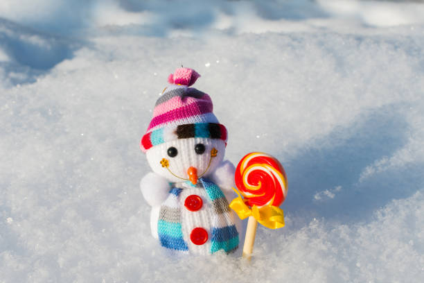 istock small knitted snowman with candy in the snow 1180227531