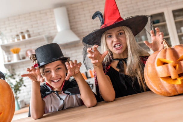 istock Childrens in suits and with pumpkins having fun on Halloween at home kitchen 1180227706