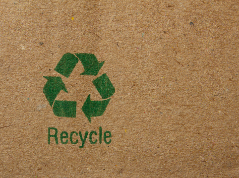 Top view close-up image of notebook with recycling symbol and text at moss background
