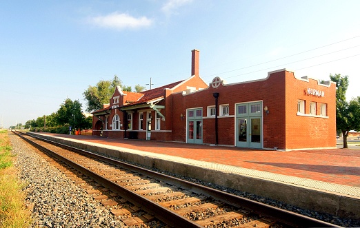 A young man standing on a train platform, waiting to catch a train while on holiday in Toulouse, France. He is looking down the railway track for his train.