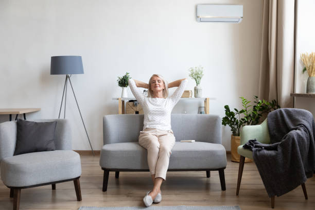 Relaxed older woman sitting on couch in air conditioner room Relaxed satisfied older woman sitting leaning back on couch in air conditioner room, happy peaceful mature female with hands behind head resting on sofa at home, enjoying fresh air, breathing midsection photos stock pictures, royalty-free photos & images