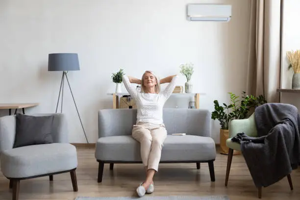 Photo of Relaxed older woman sitting on couch in air conditioner room