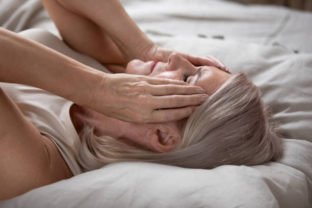 istock Exhausted mature woman lying in bed, touching temples close up 1180231117