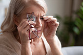 Tired older woman taking off glasses, feeling eye strain