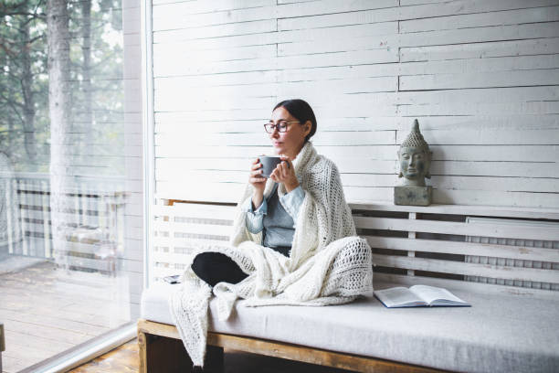 kobieta w średnim wieku siedzi wygodnie i cieszy się herbatą - winter women zen like photography zdjęcia i obrazy z banku zdjęć