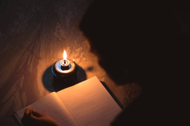 istock A student writing on notebook in a kerosene oil lamp 1180234694