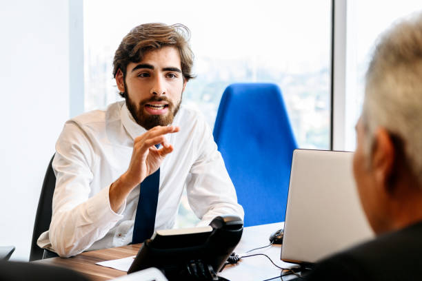 istock Young businessman gesturing with hand and talking in meeting 1180235458