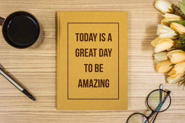 Notebook with Inspirational Quote on Wooden Work Desk. Be Amazing.