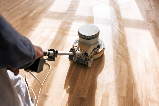 a professional master cleans the floor (parquet) with a polishing machine